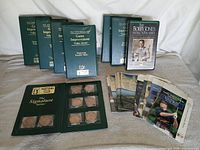 Lot overview showing medallion binder, VHS tapes, pamphlets