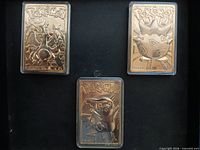 Front view of three gold-plated Pokémon cards in cases: Charizard, Togepi, Pikachu