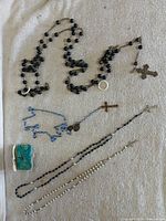 Group shot of four rosaries, coin purse and loose ring on fabric surface