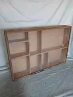 Front view of wooden shadow box display case showing compartments and clear front