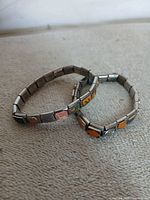 Two stainless steel charm bracelets showing overall design and link construction