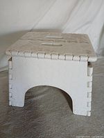 front view of folded stool showing interlocking hinges and arch opening