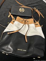 Front view of tricolor bucket bag with wallet placed on top