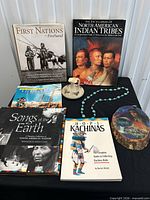 Group shot showing all books, pottery vessel, necklace and wood plaque