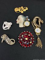 Front view of all six brooches showing designs, stones and watch faces