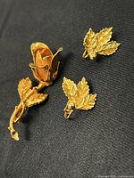 Rose pin and leaf earrings on fabric