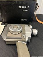 Camera laying on side with carrying case showing Sekonic Zoom 8 branding