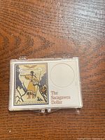 Front view of clear plastic coin holder showing printed Sacagawea insert and circular coin aperture