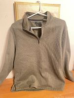Front view of olive quarter-zip pullover on hanger