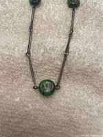 Close-up of necklace showing bar links and green glass bead