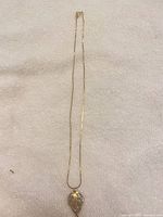 Full view of gold-tone necklace with leaf pendant