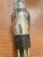 Side view showing glass envelope and etched Raytheon 37 marking on base