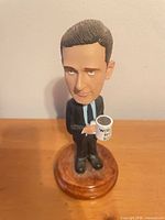 Front view of Michael Scott bobblehead holding mug on pedestal