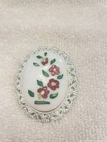 Front view showing floral porcelain cabochon and metal frame