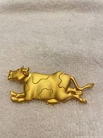 Front view of gold-tone cow brooch