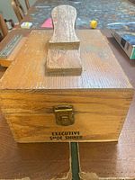 Front of wooden shoe shiner box showing latch, handle, and Executive Shoe Shiner text