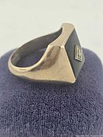 Side view of gold signet ring on display pad showing onyx face and diamond accent