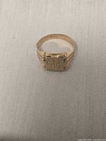 Front view of 18k gold signet ring showing engraved rectangular face
