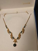 Full view of 18kt gold necklace with blue stones in Birks box