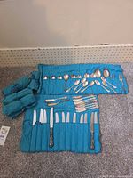 Overall view of both cloth rolls open showing assortment of knives, spoons and fork