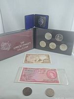 Group shot showing Chinese Dynasty Collection folder with 5 coins, boxed coin, two banknotes and two loose coins