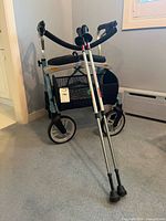 Rollator walker with pair of walking poles leaning against it