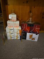 Full lot showing stacked IKEA tumbler boxes, Belfor decanter box with loose decanter, JoyJolt Alina box, and four colored flutes