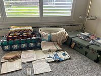 Overview of suitcase, quilts, throw, basket with linens