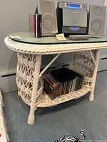 Front view of white wicker side table with glass top and lower shelf