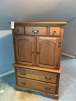 front view of wood armoire showing drawers and doors