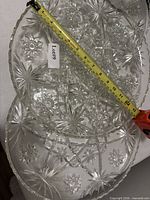 Two pressed glass serving trays with tape measure showing 13.5" length