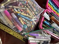 Overall view of gallon bag of crayons, quart bag of markers, pink bubble pencil case