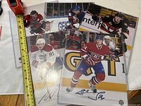 Front view of all five signed photos in sleeves with tape for scale