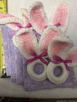 Four crochet bunny ear napkin rings stacked on four lavender napkins