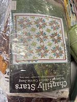 Front of Chantilly Stars quilt pattern on top of fabric pile