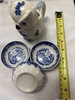 Owl pitcher beside three blue dishes, tape for scale