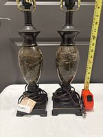 Pair of table lamps on white surface with cords and tape measure showing height