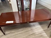 Full view of coffee table showing top, legs, and brass escutcheon