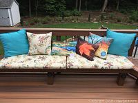 Outdoor bench with two long floral and butterfly patterned bench cushions and six decorative pillows arranged on top