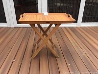 Full front view of teak serving tray on stand showing wooden slatted tray surface and folding stand.