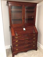 Full view of the antique mahogany secretary desk with closed desk top and glass bookcase upper section.