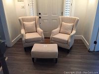 Two Arhaus Alex chairs and ottoman arranged together in front of a door on hardwood floor