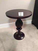Full view of the small round wooden end table showing the entire structure and silhouette.