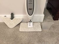 Shark professional steam mop cleaner upright with two microfiber mop heads and translucent measuring cup laid out on carpeted floor