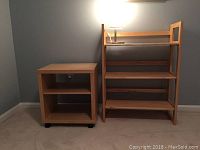 Side by side view of the blonde wood bookcase and caster end table against a light wall.