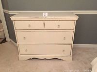 Front view of the antique dresser showing three drawers with clear glass knobs and distressed cream paint.
