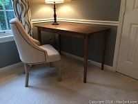 Desk and chair positioned against wall under lamp