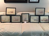 View of all 7 framed Egyptian sketches arranged on a couch showing size and framing
