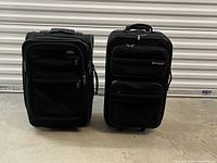 Both Samsonite suitcases upright showing size difference and overall condition