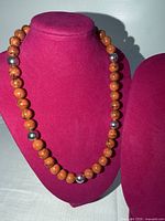 Full view of brown bead necklace on display bust